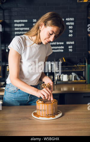 Belle femme blanc T-shirt la décoration de gâteau au chocolat avec des noix Banque D'Images