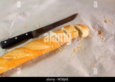 Vue de dessus de vif et frais en tranches de baguette de pain français et le couteau rétractable papper entouré par des miettes Banque D'Images