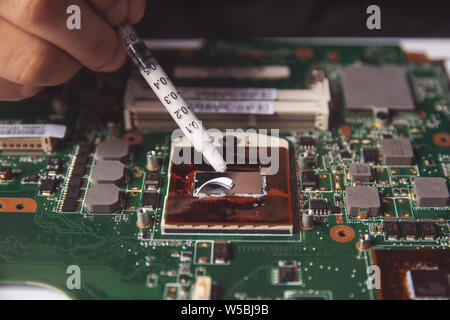 L'application de pâte thermique technicien avec la seringue sur le processeur CPU carte mère sur ordinateur portable Banque D'Images