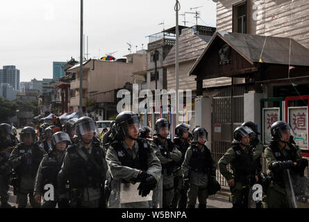 Les agents de police antiémeute montent la garde pendant les affrontements avec les manifestants.Des milliers de manifestant poursuivre leur semaine de protestation contre le gouvernement exigeant le retrait du gouvernement de pleinement le projet de loi sur l'extradition et de constituer une commission indépendante chargée d'examiner les questions de la police à l'aide d'une force disproportionnée contre des manifestant et en établissant des liens avec des membres de gangs locaux pour attaquer les manifestants la semaine dernière. La protestation a eu lieu dans le district de Yuen Long où les manifestants ont été brutalement attaqué par une foule de membres de gangs habillé en blanc la semaine dernière. Banque D'Images