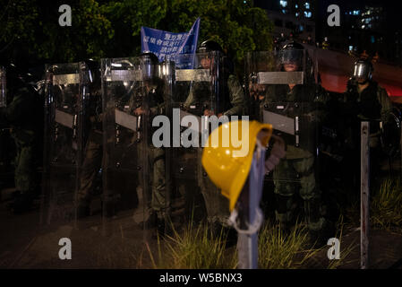 Les agents de police antiémeute montent la garde pendant les affrontements avec les manifestants.Des milliers de manifestant poursuivre leur semaine de protestation contre le gouvernement exigeant le retrait du gouvernement de pleinement le projet de loi sur l'extradition et de constituer une commission indépendante chargée d'examiner les questions de la police à l'aide d'une force disproportionnée contre des manifestant et en établissant des liens avec des membres de gangs locaux pour attaquer les manifestants la semaine dernière. La protestation a eu lieu dans le district de Yuen Long où les manifestants ont été brutalement attaqué par une foule de membres de gangs habillé en blanc la semaine dernière. Banque D'Images
