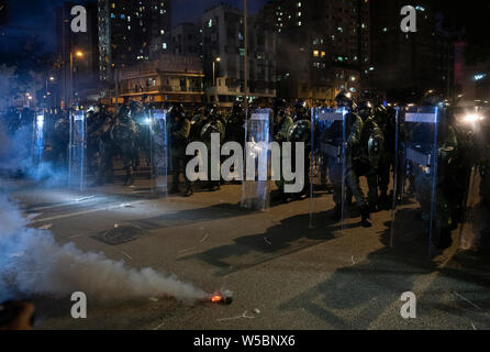 Les agents de police antiémeute montent la garde pendant les affrontements avec les manifestants.Des milliers de manifestant poursuivre leur semaine de protestation contre le gouvernement exigeant le retrait du gouvernement de pleinement le projet de loi sur l'extradition et de constituer une commission indépendante chargée d'examiner les questions de la police à l'aide d'une force disproportionnée contre des manifestant et en établissant des liens avec des membres de gangs locaux pour attaquer les manifestants la semaine dernière. La protestation a eu lieu dans le district de Yuen Long où les manifestants ont été brutalement attaqué par une foule de membres de gangs habillé en blanc la semaine dernière. Banque D'Images