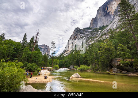 28 juin 2019 Yosemite National Park / CA / USA - Les gens se détendre et s'amuser sur les rives du lac Miroir, le long de Tenaya Creek ; demi-dôme visible Banque D'Images