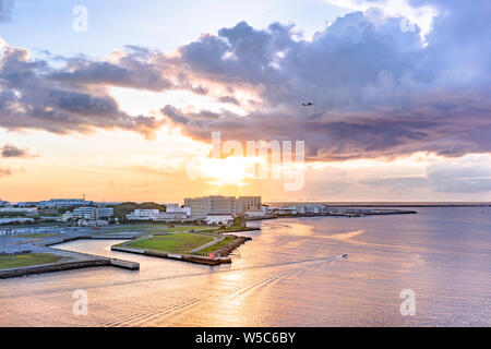 Avion survolant la mer au coucher du soleil dans le district de Sumiyoshi La ville de Naha à Okinawa island de la Loisir Hotel Banque D'Images