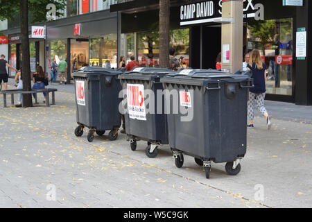 Mannheim, Allemagne - Juillet 2019 : Trois grandes poubelles noires sur roues appartenant à un magasin debout dans le centre-ville de Mannheim Banque D'Images