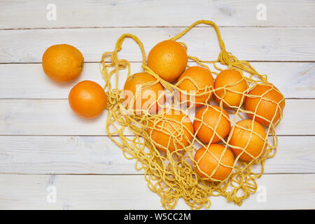 Vue de dessus d'oranges fraîches en string blanc sac sur fond rustique Banque D'Images