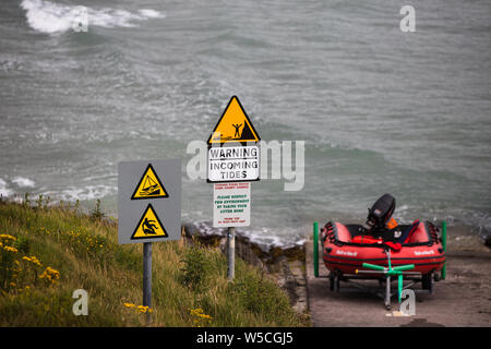 Juillet 27th, 2019, Clonakilty, Irlande - l'arrivée d'un signe d'avertissement des marées à côté d'un bateau de sauvetage près de Inchydoney beach. Banque D'Images