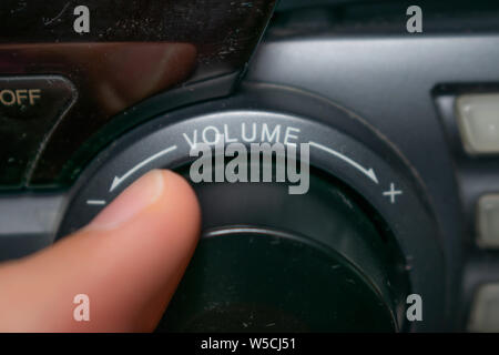 Une personne en tournant la molette du volume vers le haut ou vers le bas (l'accent est mis sur le mot 'volume' écrit sur l'appareil) Banque D'Images