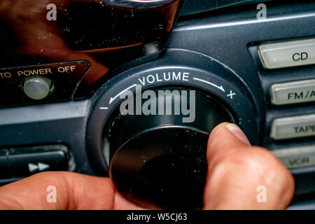 Une personne en tournant la molette du volume vers le haut ou vers le bas (l'accent est mis sur le mot 'volume' écrit sur l'appareil) Banque D'Images