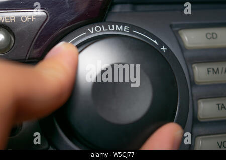 Une personne en tournant la molette du volume vers le haut ou vers le bas (l'accent est mis sur le mot 'volume' écrit sur l'appareil) Banque D'Images