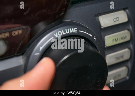 Une personne en tournant la molette du volume vers le haut ou vers le bas (l'accent est mis sur le mot 'volume' écrit sur l'appareil) Banque D'Images