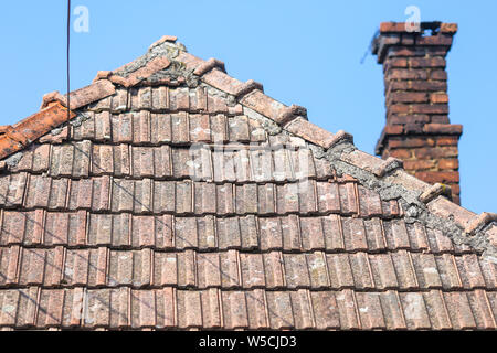 Détails avec l'ancien les tuiles et briques rouges avec la cheminée d'une maison dans un village rural en Roumanie Banque D'Images