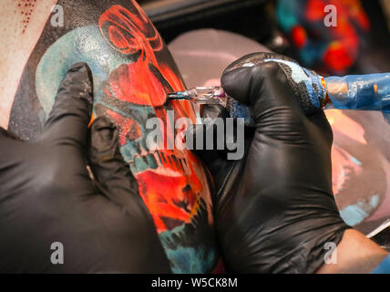 La photo en gros plan d'un tatoueur travaille sur un crâne à l'aide d'un tatouage tattoo design gun Banque D'Images
