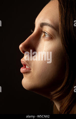 Femme triste à pleurer, à côté sur fond noir, closeup portrait, le profil Voir Banque D'Images