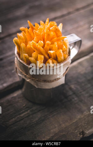 Des frites dans une tasse de métal sur un fond rustique en bois. Close-up. Shot verticale Banque D'Images