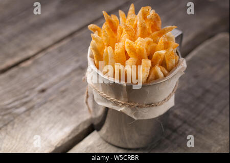 Des frites dans une tasse de métal sur un fond rustique en bois. Close-up. Copy space Banque D'Images