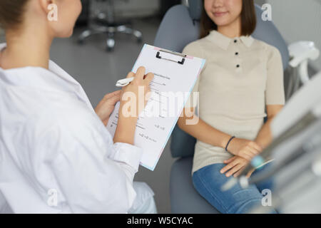 High angle view of young female dentist remplissant formulaire patients lors de la consultation enfant assis dans le fauteuil dentaire, copy space Banque D'Images