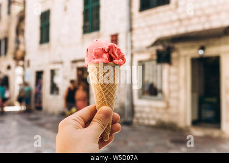Libre de fille ou femme holding ice cream de corail vivant dans des couleurs tendance waffle cup sur le fond d'une vieille rue de la ville. Banque D'Images