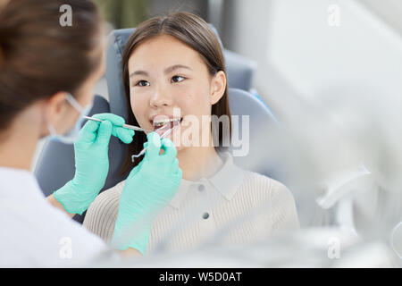 High angle portrait of smiling Asian girl sitting in fauteuil dentaire lors de l'enregistrement, copy space Banque D'Images