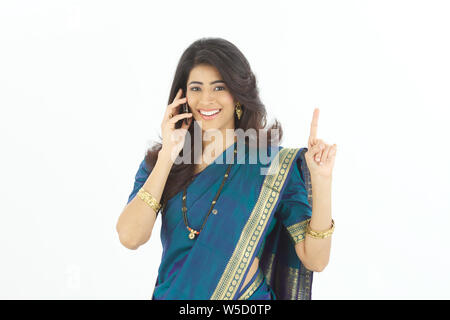 Femme parlant sur un téléphone mobile et pointant vers le haut Banque D'Images