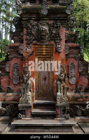 Les grandes portes d'entrée en bois décorés et pierre Bedogol comme protecteurs, Ubud, Bali, Indonésie Banque D'Images