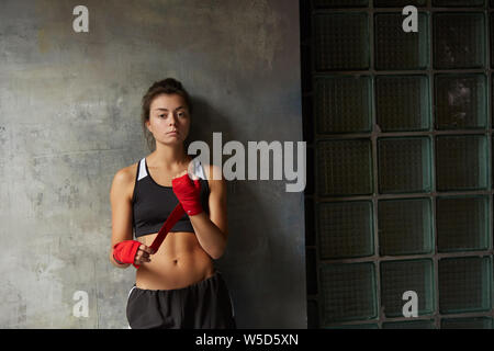 Taille portrait de femme difficile fighter portant des tours de main à la caméra à tout en se posant contre mur en béton, copy space Banque D'Images