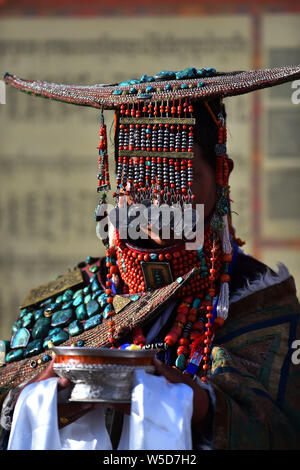 Lhasa, Chine, région autonome du Tibet. 22 juillet, 2019. Une femme portant des vêtements Burang présente highland barley wine aux visiteurs dans le comté de Burang d'Ali, le sud-ouest de la Chine, région autonome du Tibet, le 22 juillet 2019. Burang vêtements, le port traditionnel de Burang County d'Ali, a une histoire de plus de 1 000 ans. Un seul costume peut peser environ 25 kilos parce qu'il est décoré avec de l'or, argent, perles et autres bijoux. Credit : Chogo,/Xinhua/Alamy Live News Banque D'Images