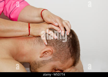 Le cou et la tête thérapeutique professionnelle. massage homme l'athlète dans une salle de massage. procédure de recouvrement de la douleur. Physiothérapeute femelle faisant manipulateur Banque D'Images