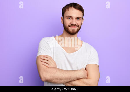 Les jeunes strong man debout les bras croisés, regardant la caméra,guy musculaire exprime des sentiments positifs . portrait, studio shot. Banque D'Images
