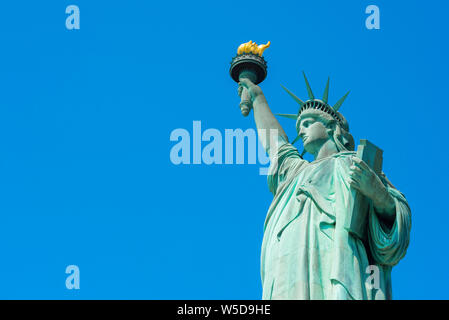 Icône symbole USA, vue de la moitié supérieure de la Statue de la liberté contre un ciel bleu clair avec copie espace gauche, Liberty Island, New York City, USA. Banque D'Images