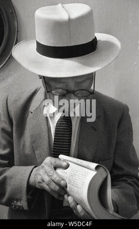 [ 1950 - Japon Japonais dans l'ouest de costume et Hat ] - Japonais homme portant un chapeau et un costume de l'Ouest est la lecture sur un navire à Awaji Island, préfecture de Hyogo, 1958 (Showa 33). Banque D'Images