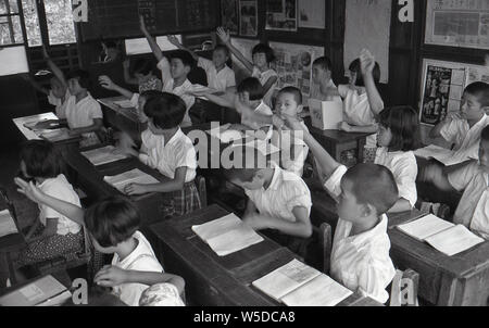 [ 1950 - Japon ] Les élèves de l'école élémentaire Japonais - japonais de l'école élémentaire, la quasi-totalité d'entre eux portant des chemises blanches, la lecture en classe, 1958 (Showa 33). Banque D'Images