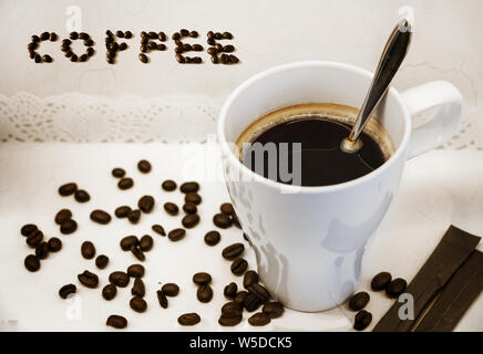 Tasse de café avec une cuillère, les grains de café et café avec du texte sur fond blanc. Banque D'Images