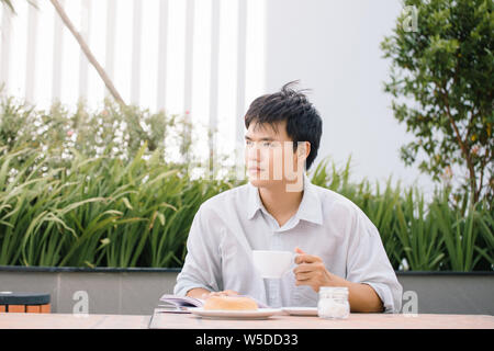 Portrait d'un bel homme de lire un livre et profiter de son café. Banque D'Images