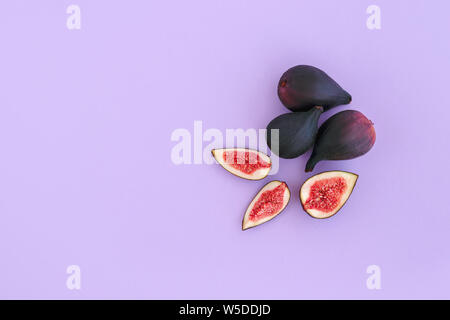 Figues coupées mûrs sur fond violet. Copier l'espace. Vue d'en haut. Banque D'Images