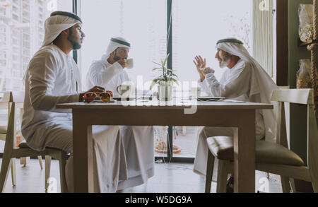 Trois hommes d'affaires ayant un plateau à Dubaï portant des vêtements traditionnels emirati Banque D'Images