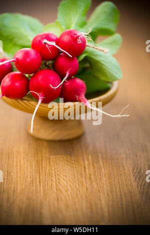 Produits frais bio radis rouge avec des feuilles sur une table en bois Banque D'Images