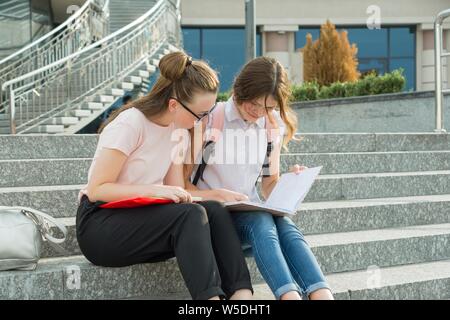 Portrait plein air de deux jeunes belles filles élèves avec des sacs à dos, livres. Les filles de parler, à la livre, en milieu urbain Banque D'Images