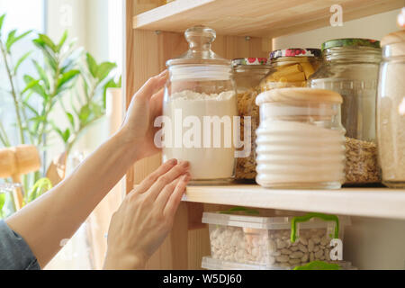 Les produits alimentaires dans la cuisine le stockage des ingrédients dans un garde-manger. Woman taking pot de farine Banque D'Images