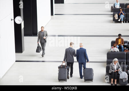 Voir ci-dessus des hommes en costumes transport des bagages et se déplaçant le long d'aéroport tout en se dépêchant pour l'embarquement Banque D'Images