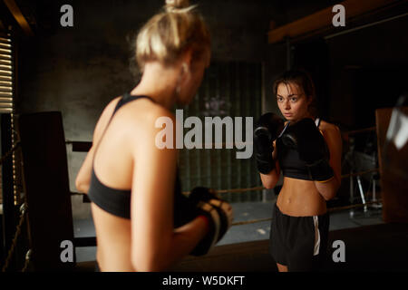 Jusqu'à la taille spectaculaire portrait de deux femmes boxers fighting in ring, copy space Banque D'Images