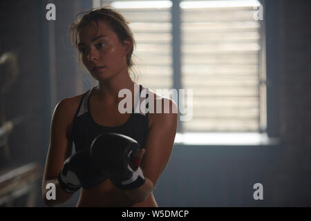 Tons sombres portrait de jeune femme en sueur pratiquer la boxe au club de sport, copy space Banque D'Images