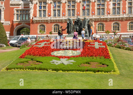 De fleurs en face de l'Hôtel de Ville, Calais, France avec le bronze des Bourgeois de Calais par Rodin Banque D'Images