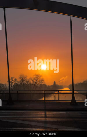 Voir à travers un pont arc à un lever de soleil sur un canal à Berlin sur un matin brumeux avec fairytale du soleil. Banque D'Images