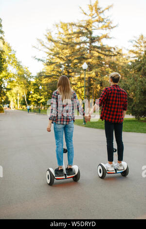 Jeune couple riding sur gyroboard en Parc, Vue arrière Banque D'Images