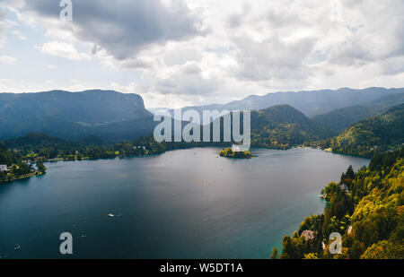 Vue aérienne du lac de Bled en Slovénie entouré de montagnes et de forêts et l'île de Bled. Avec Resorts, hôtels, maisons, parcs et plages loca Banque D'Images