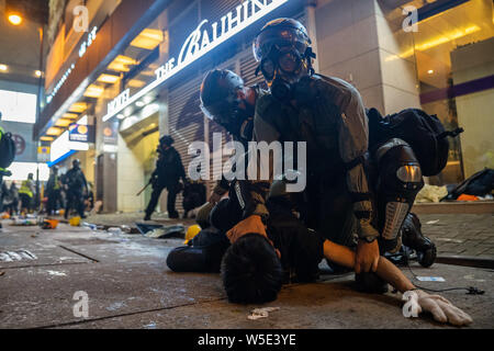 Les agents de la police anti-émeute, tenir un manifestant au sol comme ils l'arrêter pendant la manifestation.Des dizaines de milliers de manifestants pro-démocratie ont défilé dans le centre de Hong Kong à une nouvelle série de démonstration anti gouvernement. La police anti-émeute a utilisé des gaz lacrymogènes et des balles de moellons contre les manifestants en dépit du fait que la police a été largement salué par le public pour leur usage disproportionné de la force contre les manifestants au cours des manifestations déclenchées par le controversé projet de loi sur l'extradition présentée par le gouvernement de Hong Kong. Banque D'Images