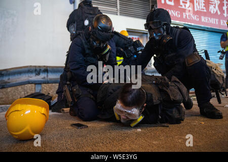 Les agents de la police anti-émeute, tenir un manifestant au sol comme ils l'arrêter pendant la manifestation.Des dizaines de milliers de manifestants pro-démocratie ont défilé dans le centre de Hong Kong à une nouvelle série de démonstration anti gouvernement. La police anti-émeute a utilisé des gaz lacrymogènes et des balles de moellons contre les manifestants en dépit du fait que la police a été largement salué par le public pour leur usage disproportionné de la force contre les manifestants au cours des manifestations déclenchées par le controversé projet de loi sur l'extradition présentée par le gouvernement de Hong Kong. Banque D'Images