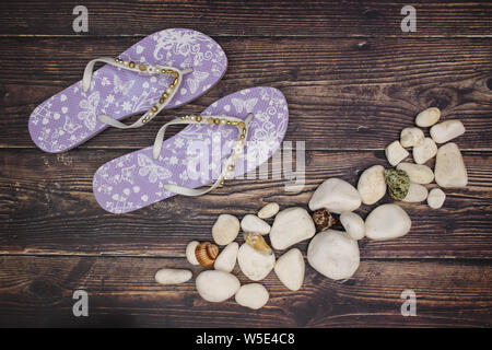 Les roches blanches et les coquillages avec chaussons violet sur fond de bois Banque D'Images