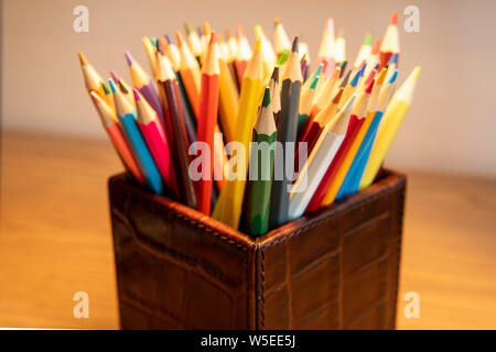 Gamme de crayons de couleur aiguisé debout dans une boîte recouverte de cuir Banque D'Images